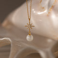 North Star Pearl Necklace in 18K Gold features a star-shaped pendant with sparkling diamonds and a dangling pearl, elegantly displayed on a white seashell—a stunning piece for any pearl jewelry collection.