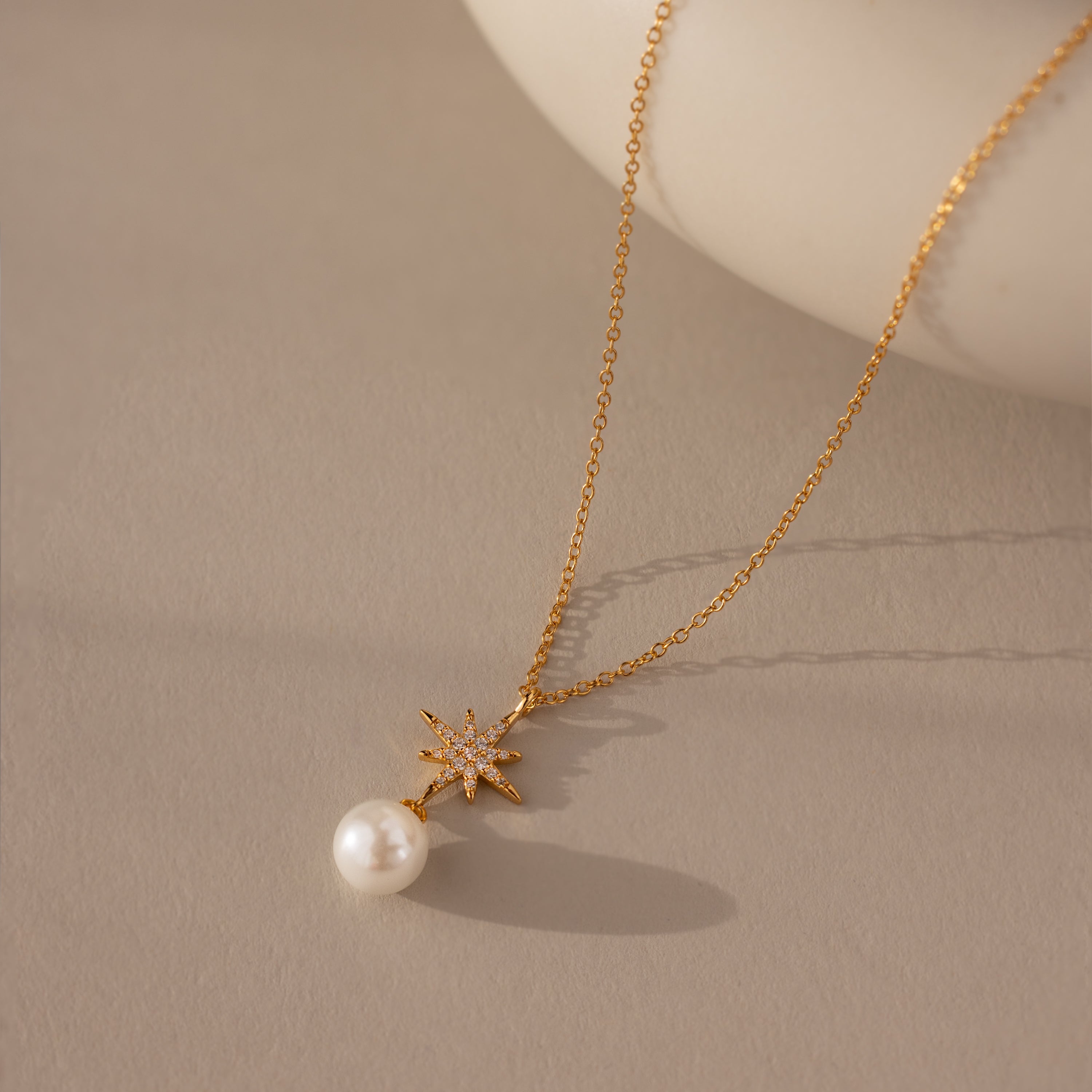 The North Star Pearl Necklace features a star pendant and single pearl, elegantly showcased on a neutral background—an ideal choice for fans of modern pearl jewelry.