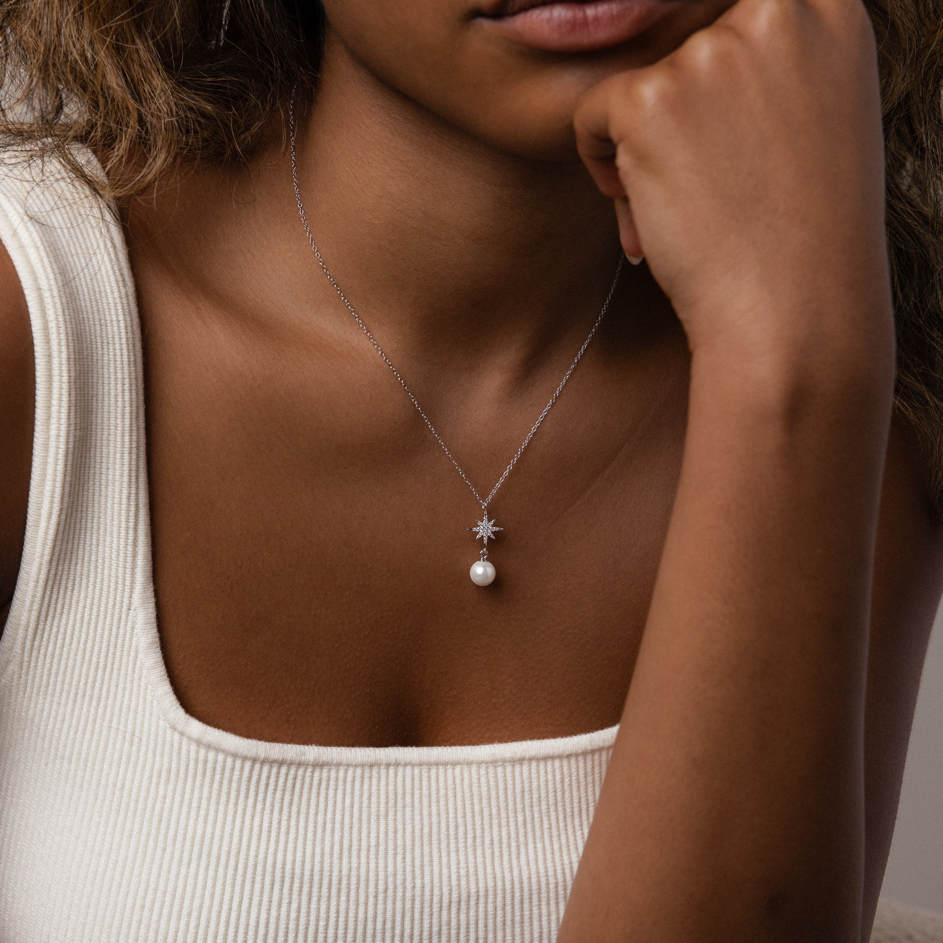 Woman wearing a white tank top and the North Star Pearl Necklace in Sterling Silver, featuring a pearl and star-shaped pendant—perfect for fans of elegant pearl jewelry.