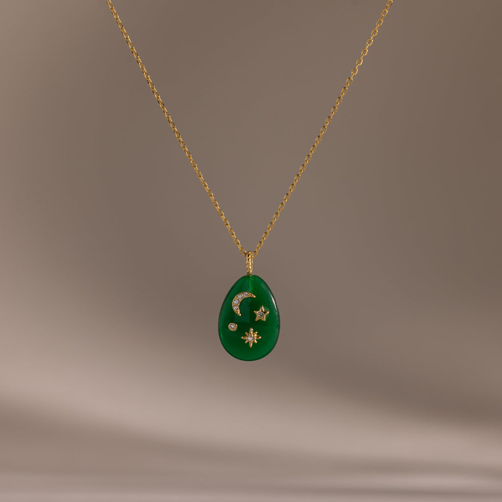 The Celestial Jade Pendant Necklace features a gold chain and green teardrop pendant with crescent moon, star, and diamond accents.