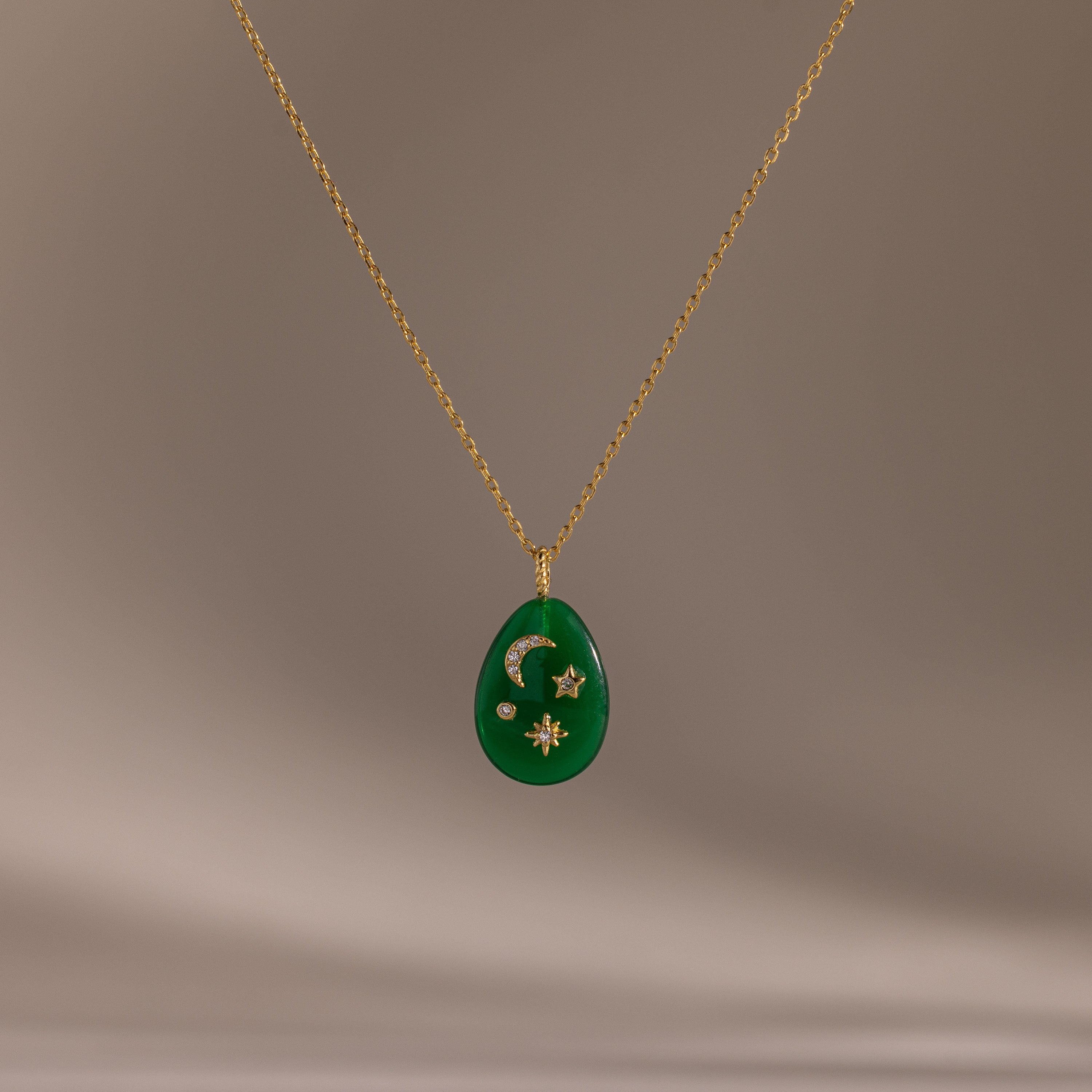 The Celestial Jade Pendant Necklace features a gold chain and green teardrop pendant with crescent moon, star, and diamond accents.