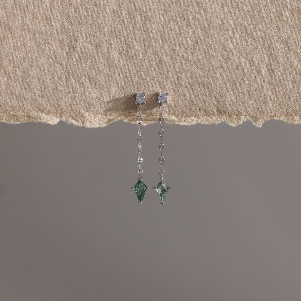Agate Diamond Dangle Earrings in Sterling Silver featuring green faceted agate stones, shown on textured beige paper with a gray backdrop.