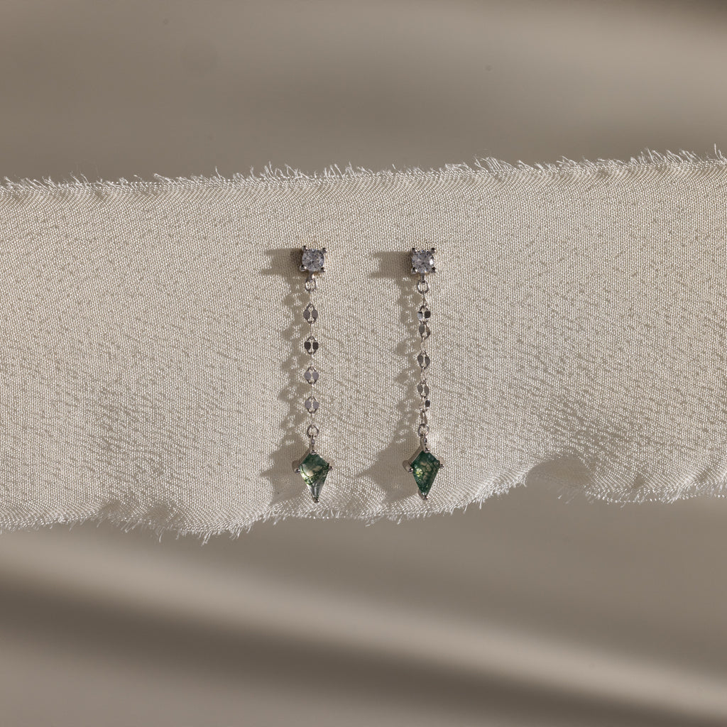 Agate Diamond Dangle Earrings in Sterling Silver, with faceted agate stones, diamonds, and green gemstones on a mirror chain, are elegantly displayed on textured cream fabric.