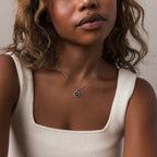 A woman in a cream tank top wears the Onyx Star Pendant Necklace in Sterling Silver, featuring a small round black onyx.