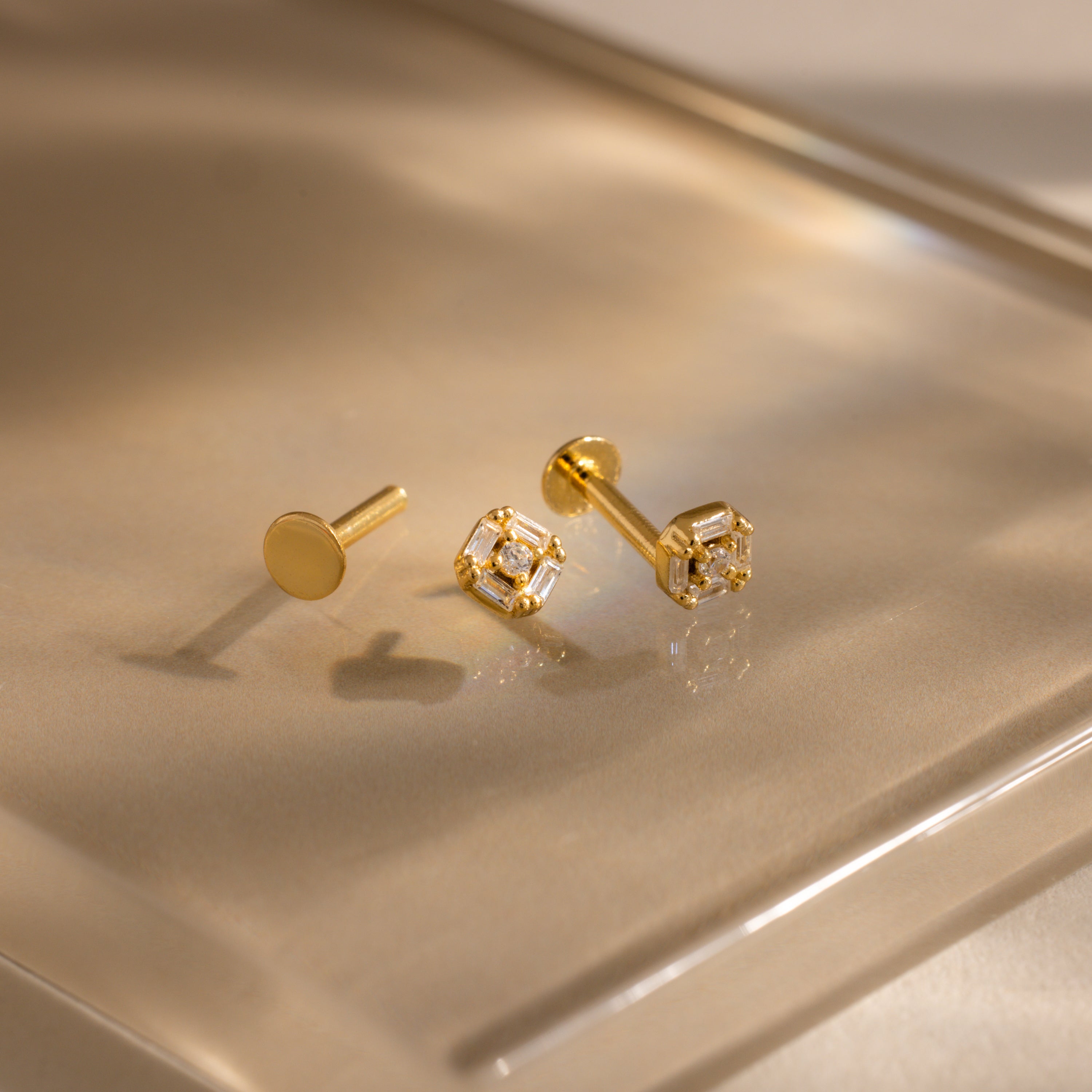 Set of gold flatback earrings shown apart—post, backing, and diamond Art Deco head on glossy surface.