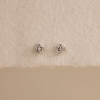 Pair of silver Art Deco flatback earrings with diamond center, styled on torn edge cream paper.