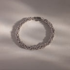 A luxury jewelry piece, the Bold Byzantine Bracelet in White Gold showcases intricate links, elegantly presented on a neutral, softly lit surface.