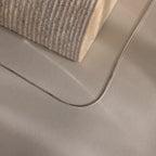 The Dainty Herringbone Necklace is displayed resting on a beige surface beside a textured block.