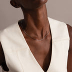 A person wearing a cream sleeveless top and the Dainty Herringbone Necklace in Sterling Silver, head tilted back.