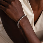 A person wears a Byzantine Link Bracelet in White Gold, featuring an elegant interwoven pattern, paired with a sleeveless cream-colored top.