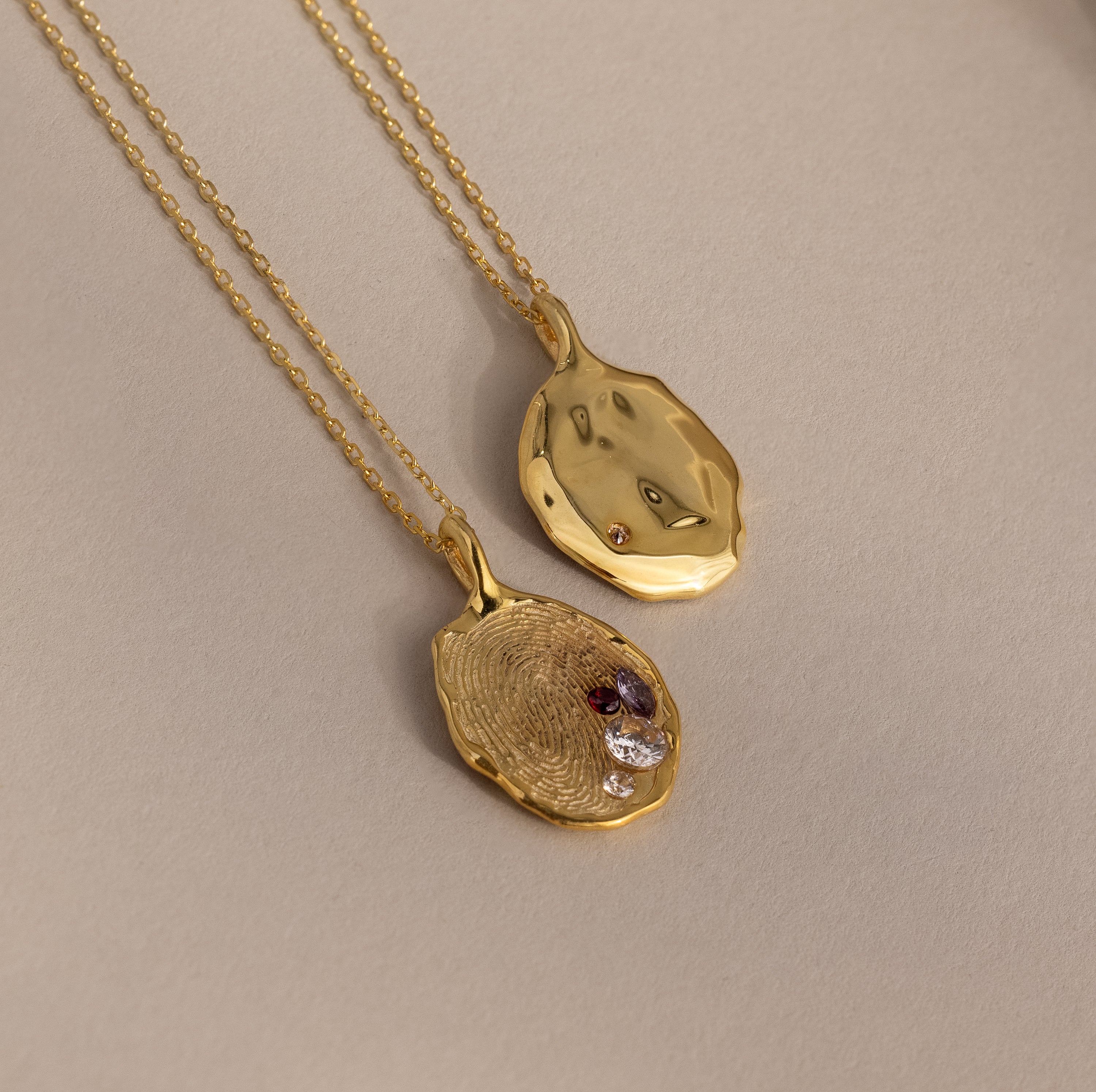 The Organic Fingerprint Multi Birthstone Necklace features two gold pendants—one plain, one textured with birthstones—creating a meaningful personalized keepsake and perfect family necklace for treasuring special memories.
