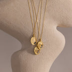 The Organic Fingerprint Multi Birthstone Necklace in 18K Gold, featuring personalized gemstones, is displayed on a curved, textured beige mannequin bust.