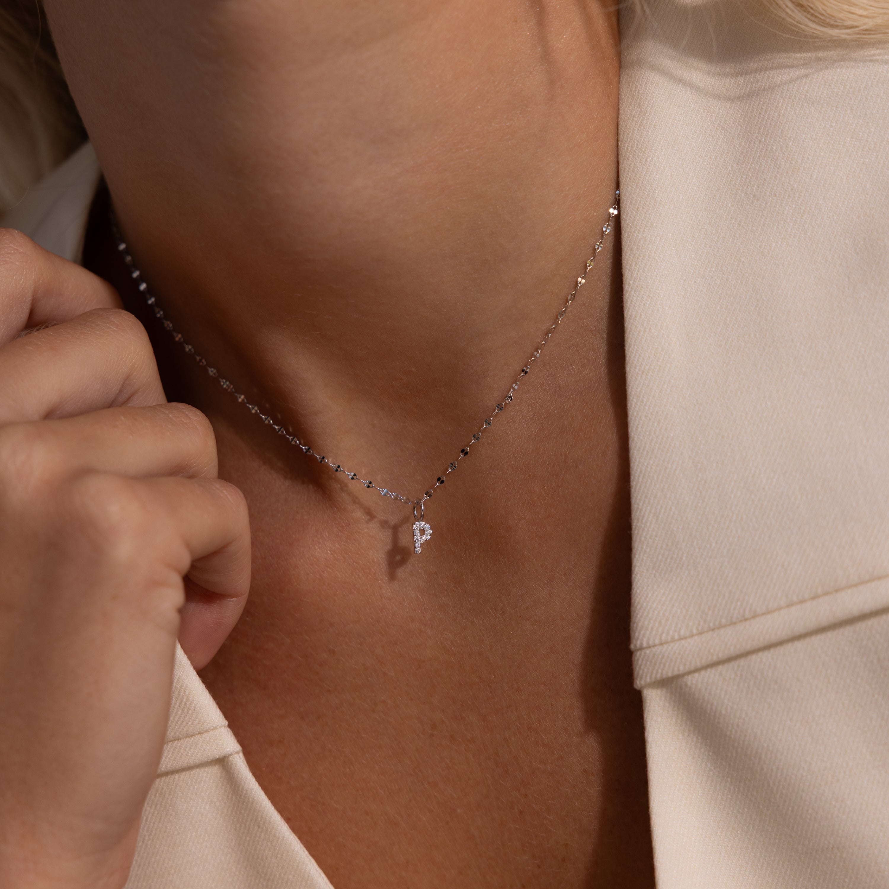 A woman wears the Dainty Pave Letter Necklace in Sterling Silver, featuring a delicate silver chain and a pavé pendant shaped like the letter P.