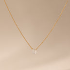 Minimalist jewelry: Teardrop Moonstone Necklace with a gold chain and a single moonstone pendant, shown against a neutral beige background.