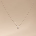 A delicate sterling silver necklace featuring a teardrop moonstone pendant, perfect for lovers of minimalist jewelry, displayed on a beige background.