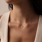 A woman wears the Teardrop Moonstone Necklace in 18K Gold, featuring a delicate chain and small oval pendant, shown from shoulders to chin.
