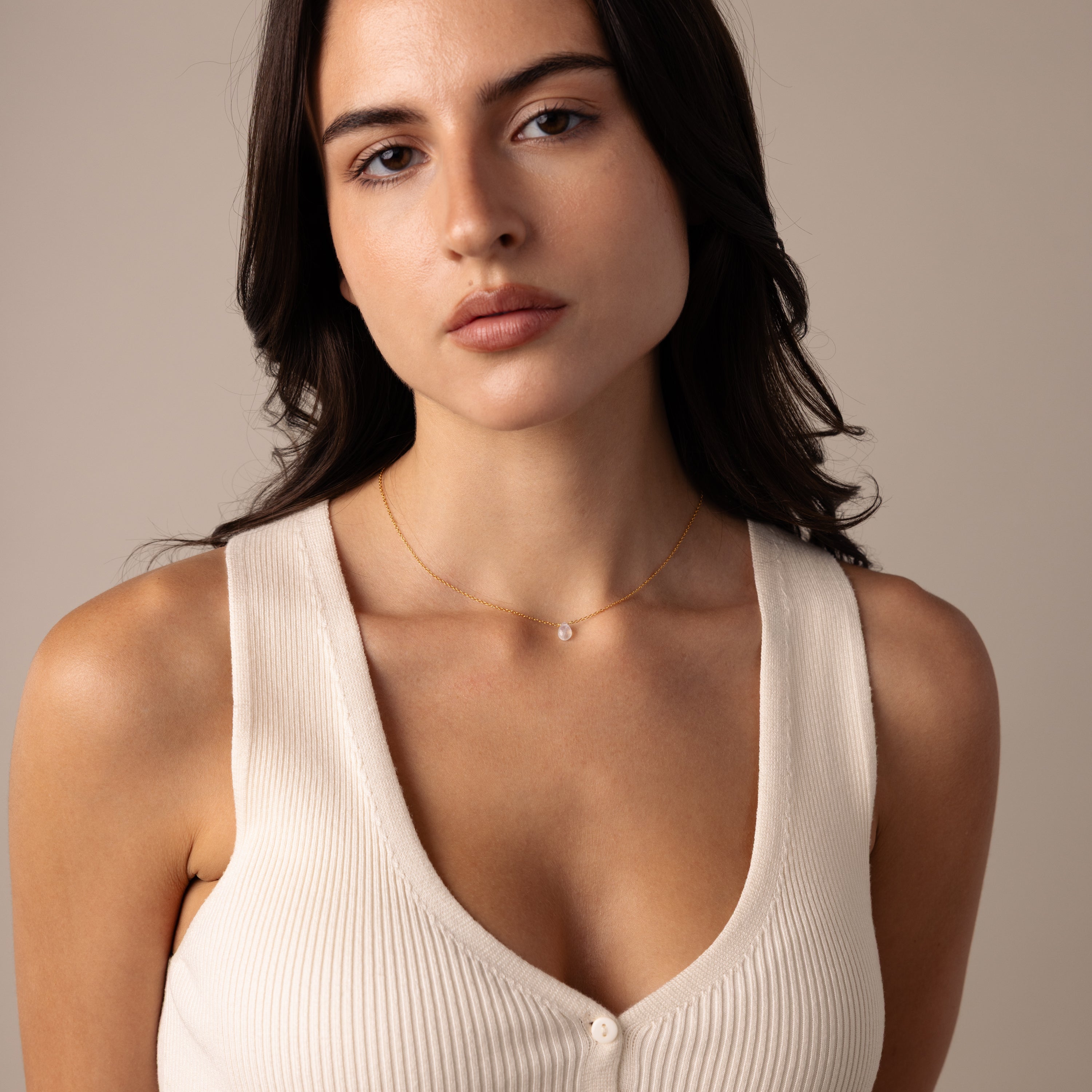 Woman with long dark hair wearing a cream sleeveless top and the Teardrop Moonstone Necklace in 18K Gold.