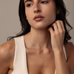 Woman with long dark hair wearing a sleeveless beige top and a Teardrop Moonstone Necklace in Sterling Silver, looking to the side.