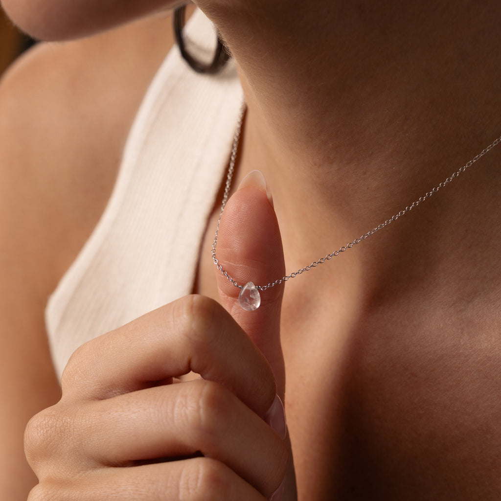 A person holds the Teardrop Moonstone Necklace in Sterling Silver, featuring a clear teardrop pendant—an ideal choice for minimalist jewelry lovers.
