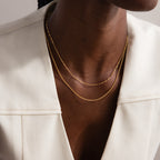 A person in a cream blazer wearing two delicate gold chain necklaces, including a minimalist necklace and the Dot Station Necklace in Sterling Silver.