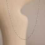 The Dot Station Necklace in Sterling Silver is displayed on a blurred, beige background.