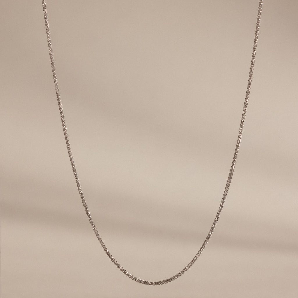 A delicate Woven Chain Necklace in Sterling Silver showcased against a soft beige background.