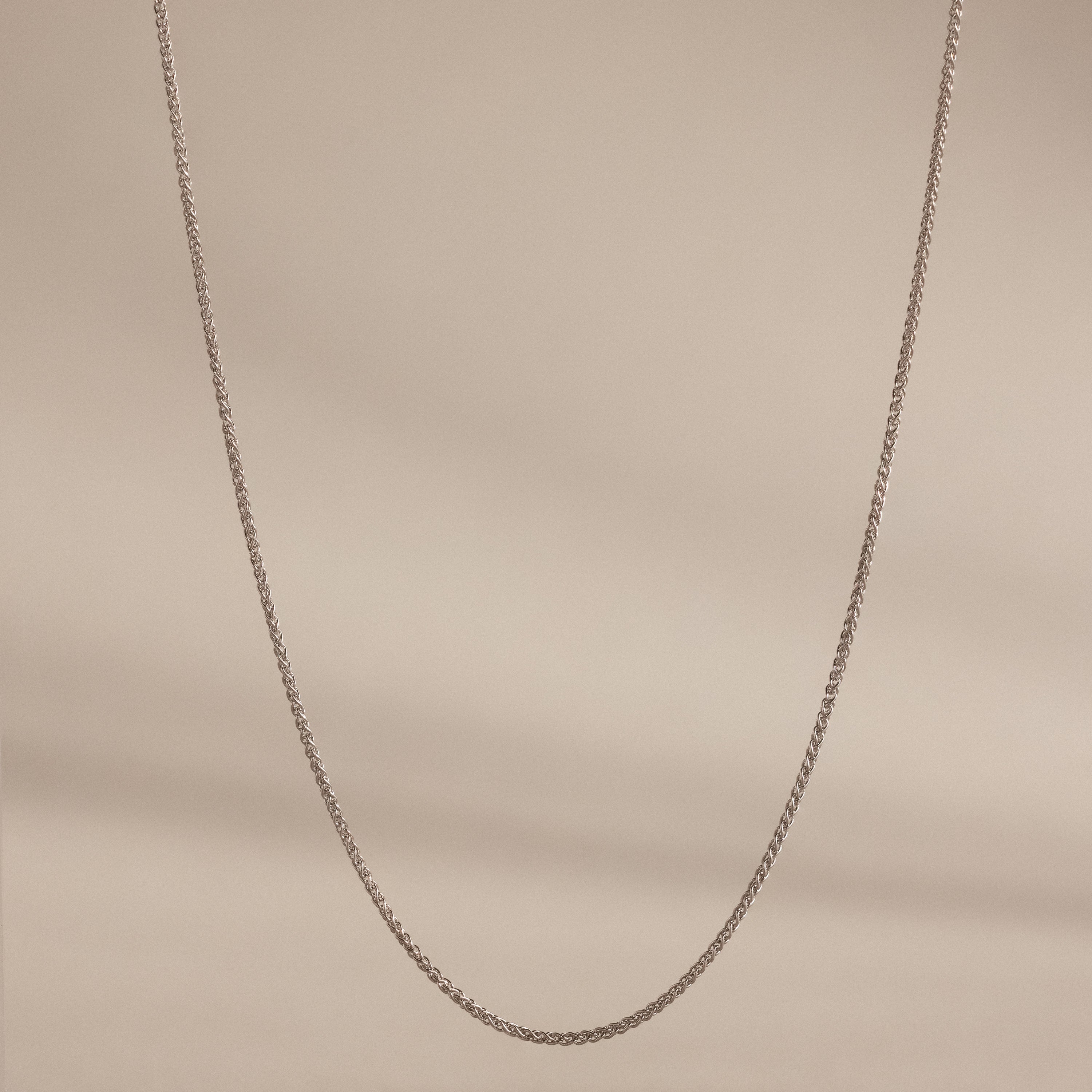 A delicate Woven Chain Necklace in Sterling Silver showcased against a soft beige background.