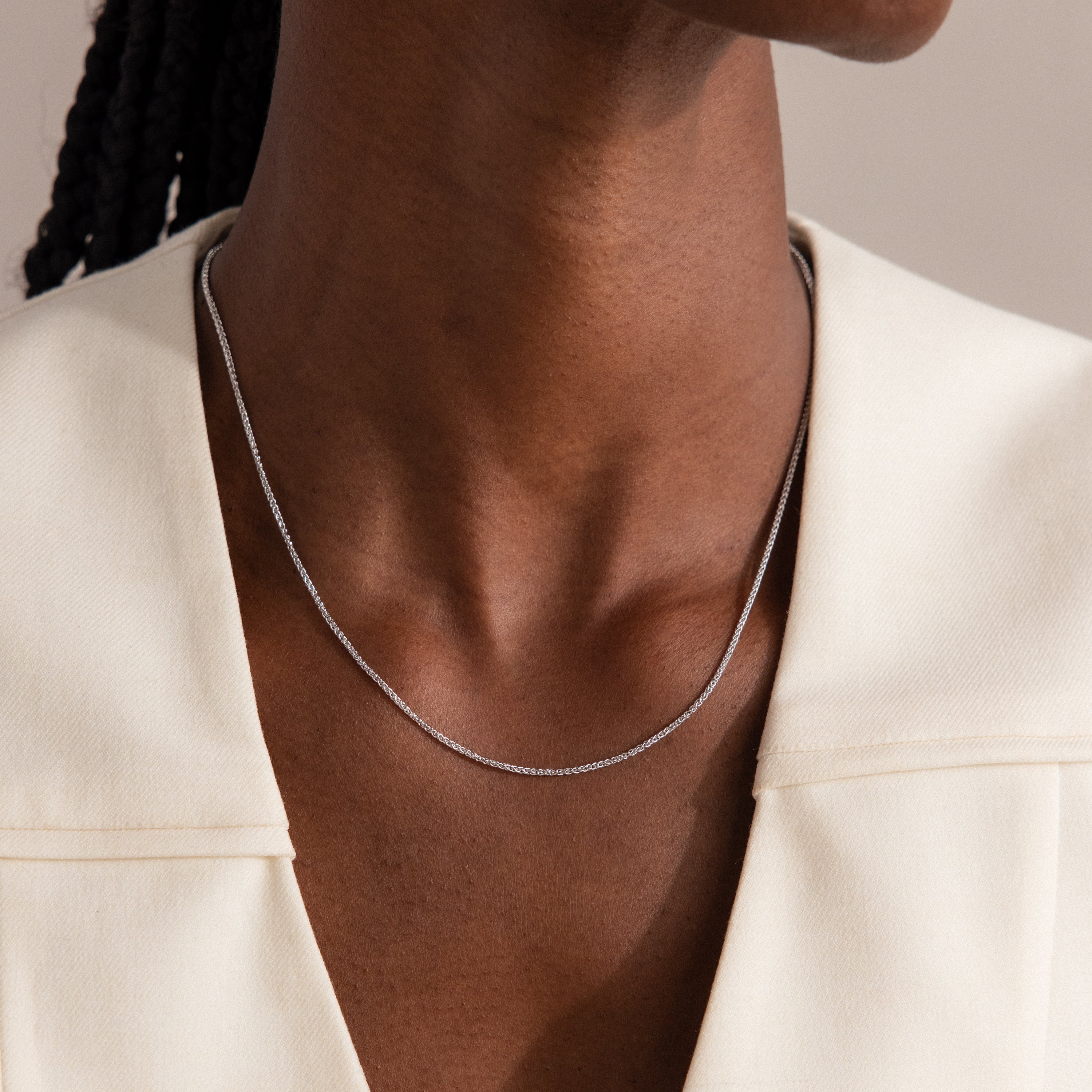 A person wearing the Woven Chain Necklace in Sterling Silver with a cream-colored top.