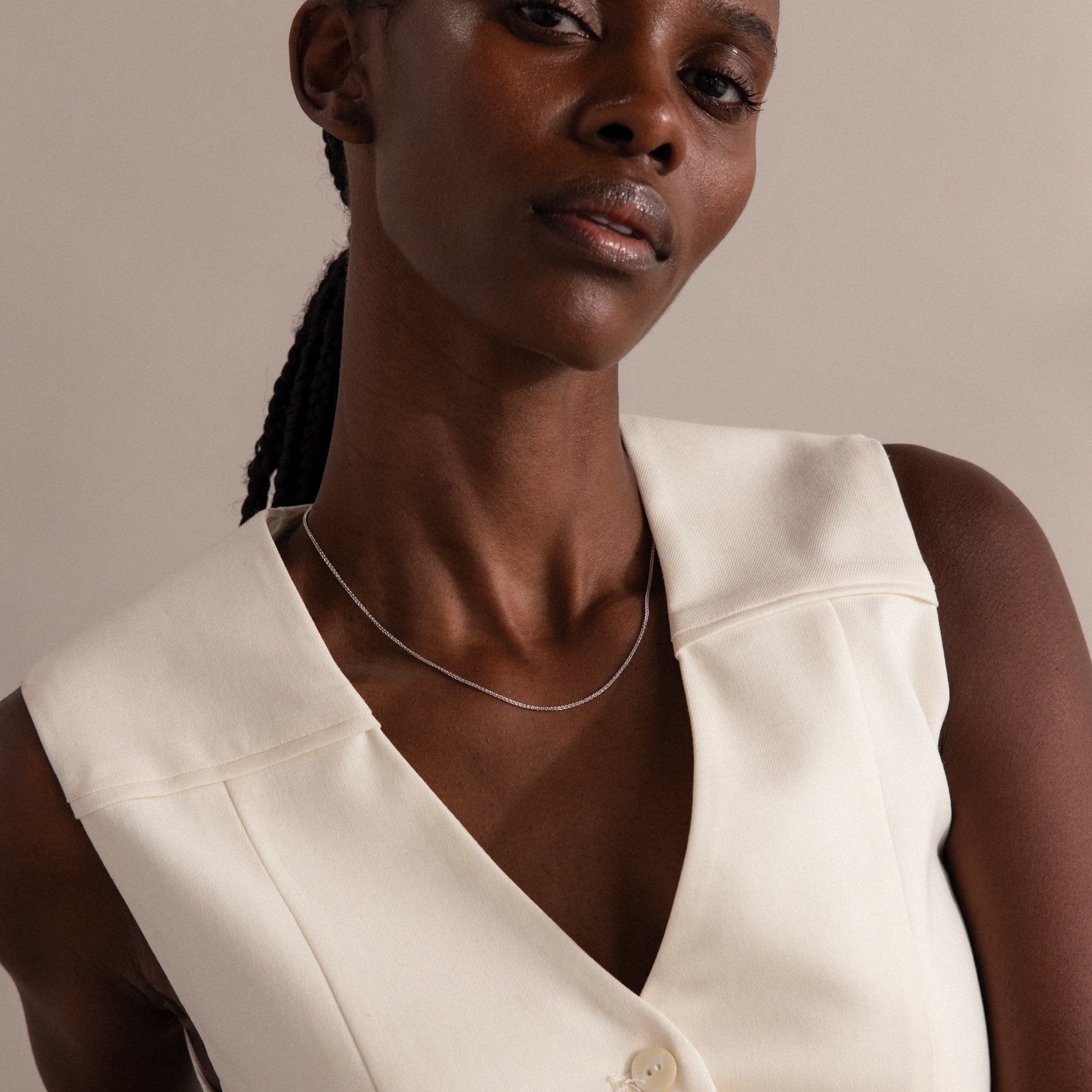 A woman in a sleeveless cream-colored top wears the Woven Chain Necklace, gazing confidently at the camera.