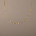 The Sprinkle Diamond Necklace in 18K Gold features a delicate chain adorned with small, evenly spaced diamonds, shown against a plain beige background.