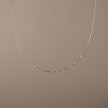 The Sprinkle Diamond Necklace in Silver, featuring delicate, evenly spaced beads, is displayed against a plain beige background.