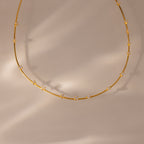 The Sprinkle Diamond Necklace in 18K Gold features delicate gold layering and small, evenly spaced diamonds, showcased on a neutral beige background.