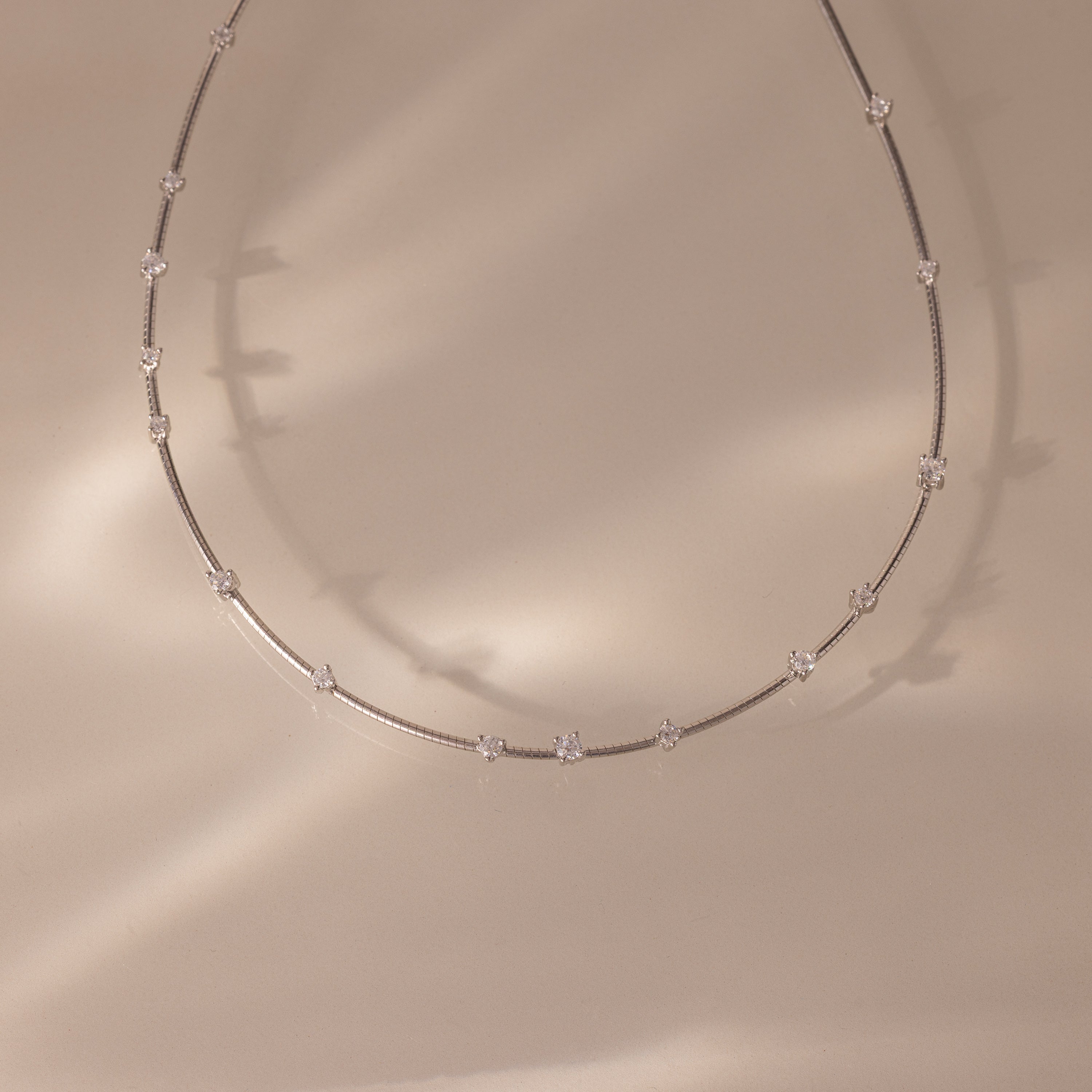 The Sprinkle Diamond Necklace in Silver features a fine, delicate chain with small, evenly spaced diamonds on a soft beige background. Perfect for layering and adding an elegant touch to any look.