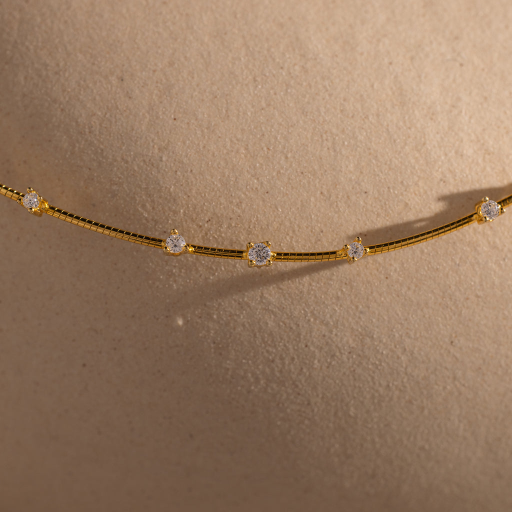 The Sprinkle Diamond Necklace in 18K Gold features delicate diamonds that shine beautifully against smooth, beige skin.