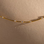The Sprinkle Diamond Necklace in 18K Gold features delicate diamonds that shine beautifully against smooth, beige skin.