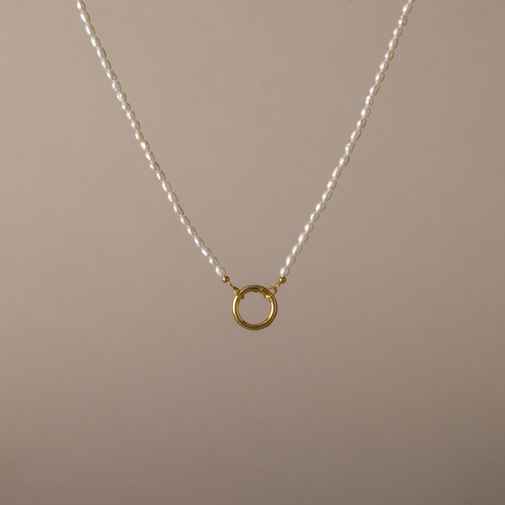 Pearl Chain Clasp Necklace in 18K Gold, featuring a gold circular pendant and shown on a beige background—a timeless piece for any jewelry collection.