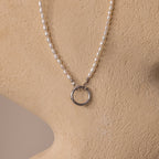 The Pearl Chain Clasp Necklace in Silver, from our jewelry collection, features luminous pearls and a silver ring pendant, elegantly displayed on a beige mannequin bust.