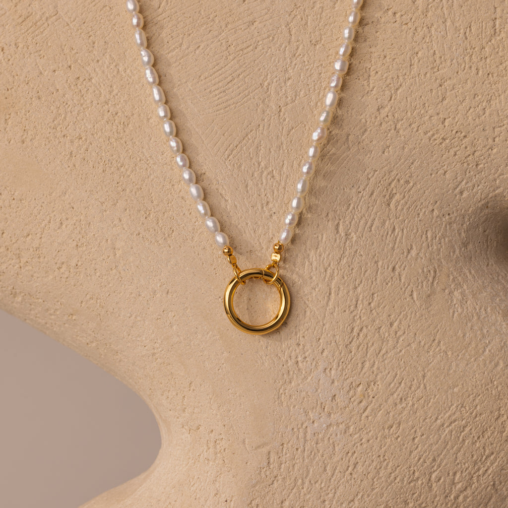 Pearl Chain Clasp Necklace in 18K Gold, shown on a beige bust with a gold circular pendant—an elegant addition to any jewelry collection.