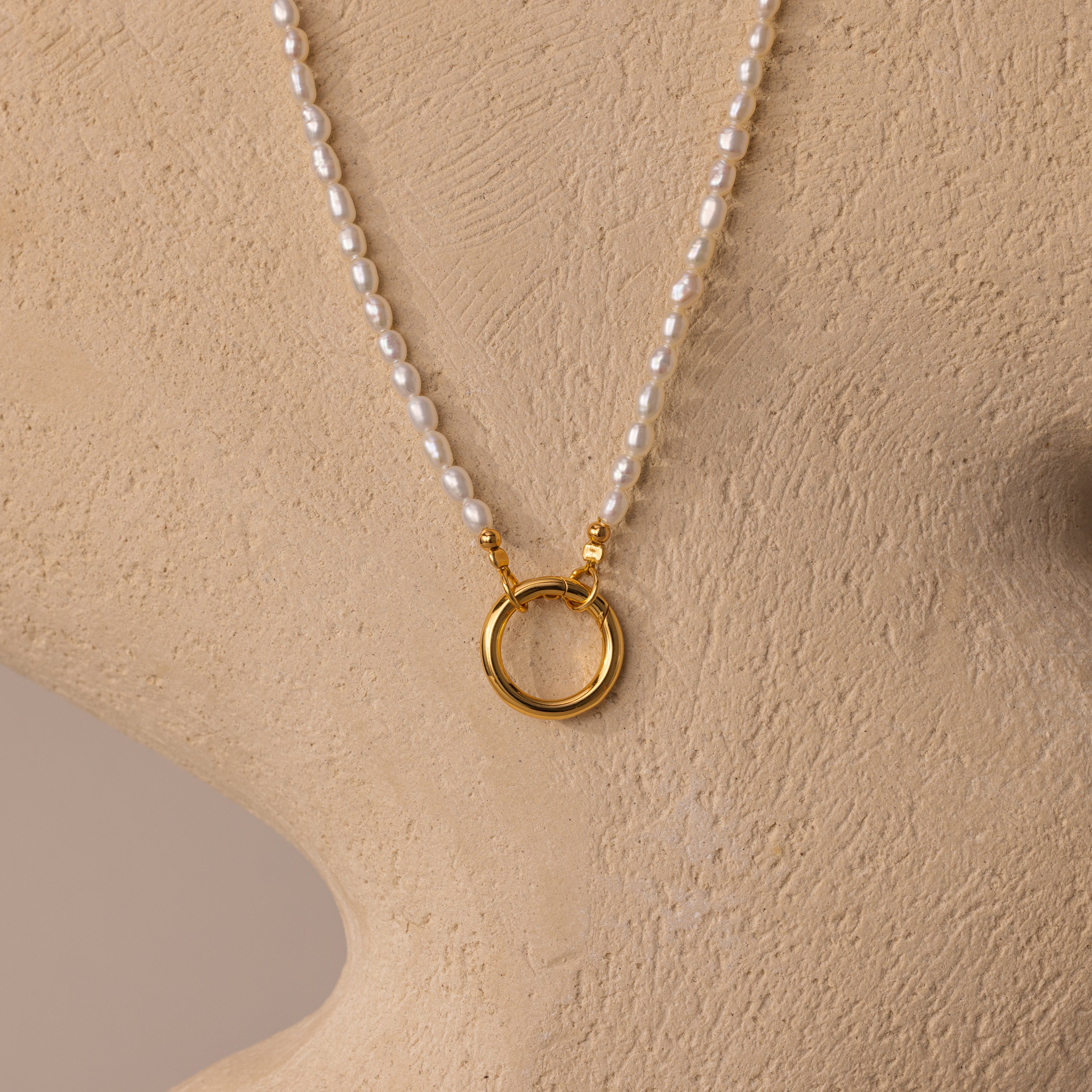 Pearl Chain Clasp Necklace in 18K Gold, shown on a beige bust with a gold circular pendant—an elegant addition to any jewelry collection.