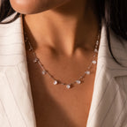 A woman wearing the Satellite Diamond Necklace in Silver with clear beads, paired with a white pinstriped blazer.