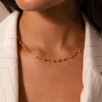 A woman wears the Sprinkle Diamond Necklace in 18K Gold, a delicate piece with small stones, paired with a cream pinstripe blazer.