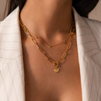 Woman wearing a white pinstripe blazer and layered gold necklaces, including the Paperclip Heart Charm Necklace in 18K Gold with delicate heart pendants.