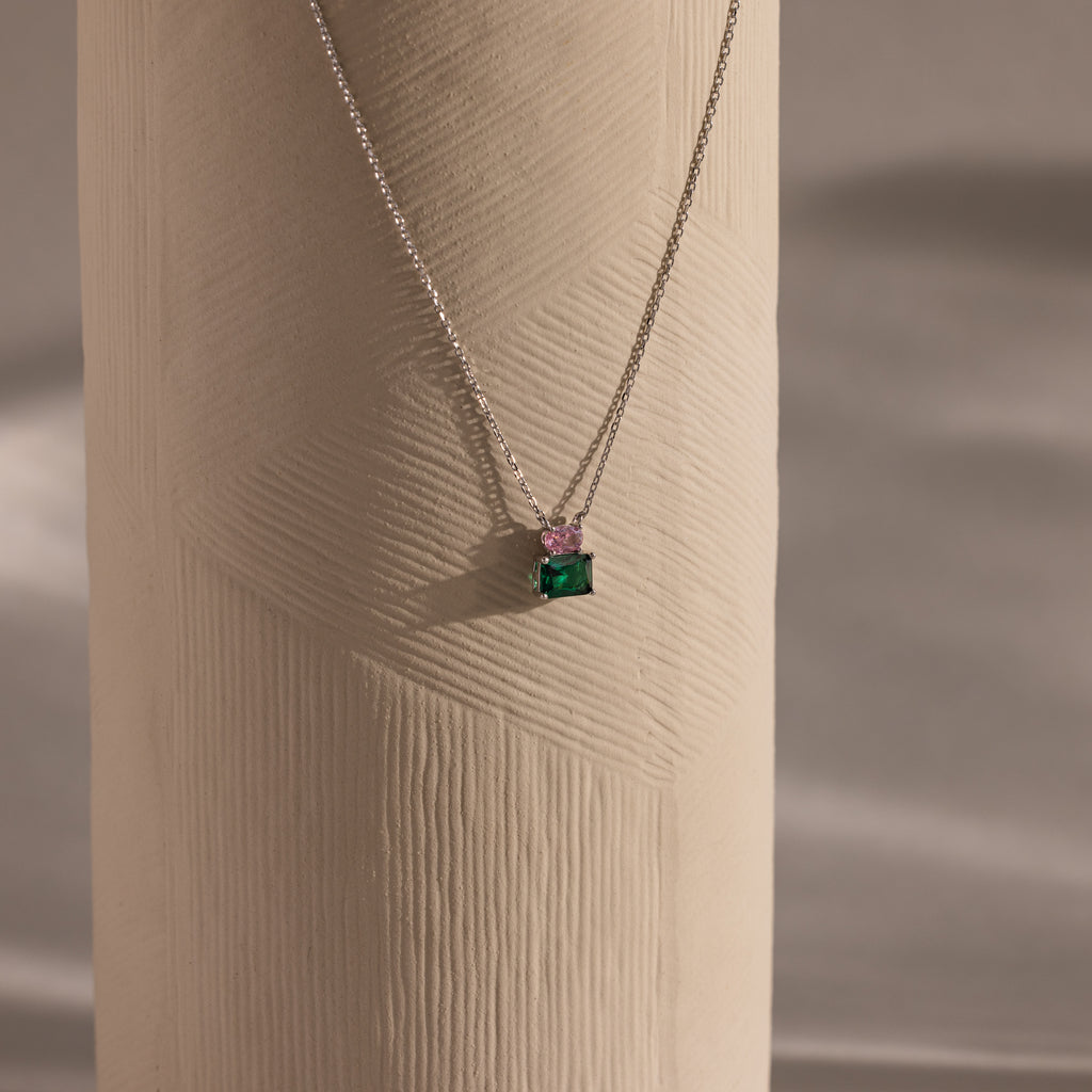 Flatlay of our Emerald Bloom Necklace with Pink Tourmaline and Emerald gemstones.