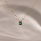 Flatlay of our Emerald Bloom Necklace with Pink Tourmaline and Emerald Gemstones