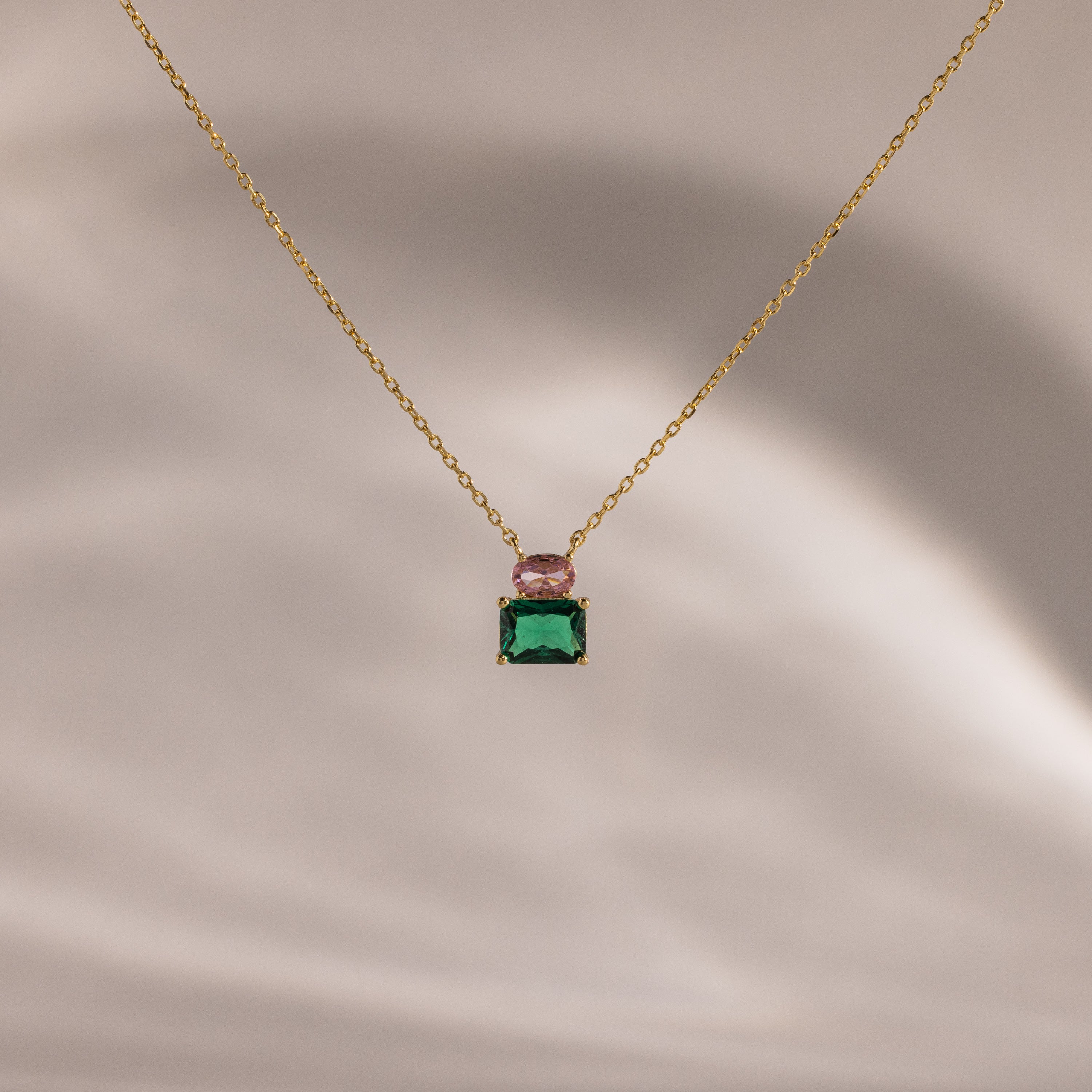 Flatlay of our Emerald Bloom Necklace with Pink Tourmaline and Emerald Gemstones