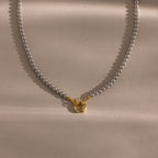 Pearl necklace with a gold clasp on a beige background