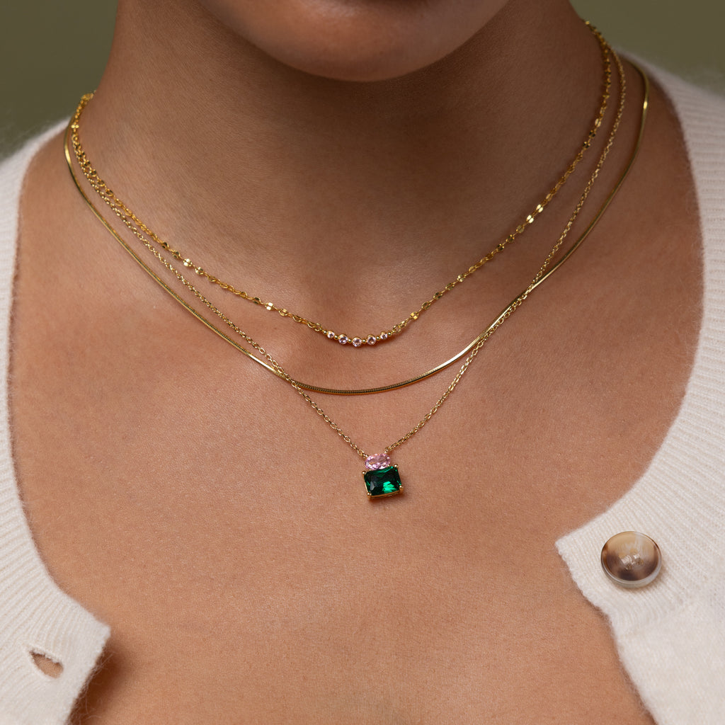Model wearing our Emerald Bloom Necklace, styled with our Josephine necklace and Herringbone necklace chains.