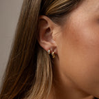 Styled photo of a model wearing an earring stack with our Diamond Leaf Hoops in Gold