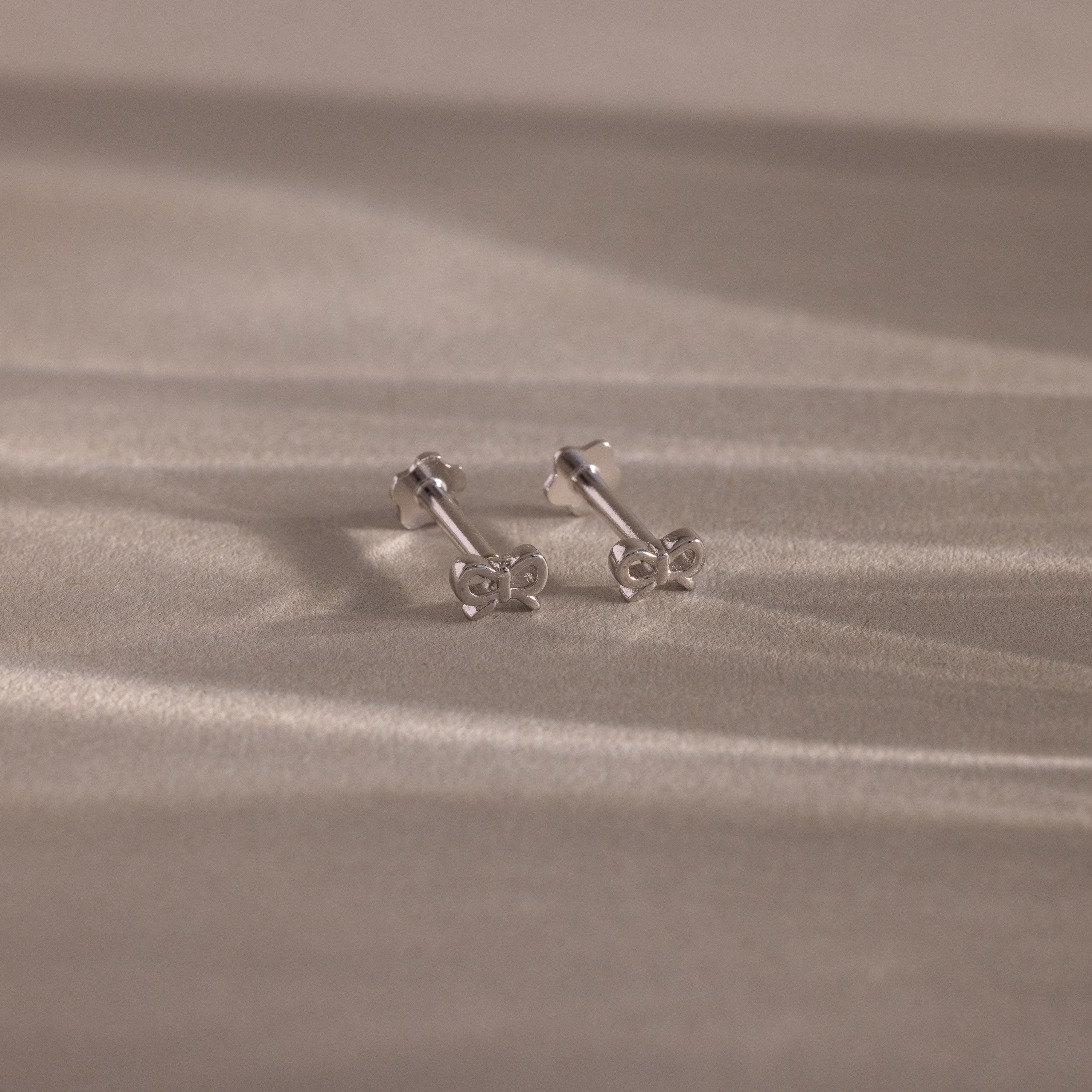 Flatlay image of our Tiny Bow Flatback Studs in Sterling Silver