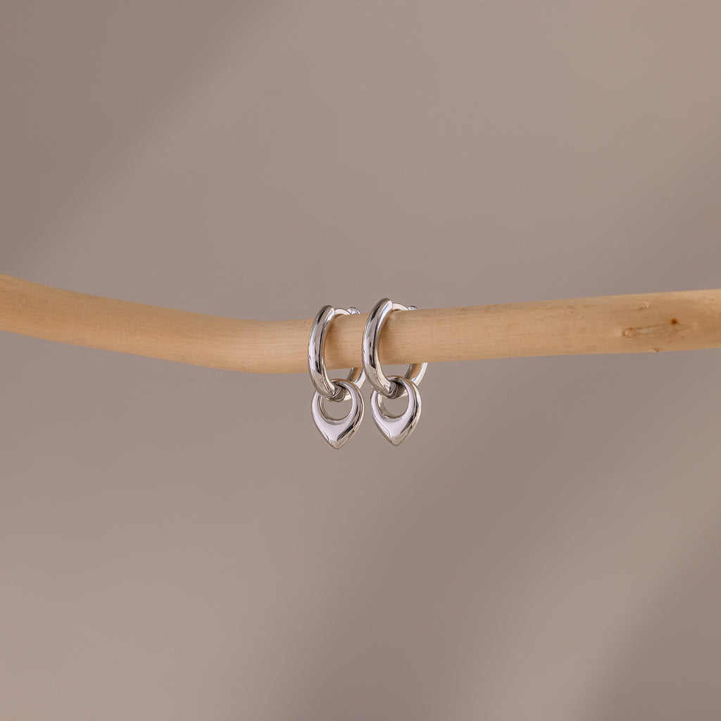 Flatlay of our Tiny Teardrop Huggies in White Gold